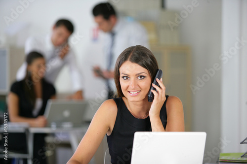 Cadre commercial souriante téléphonant devant un ordinateur