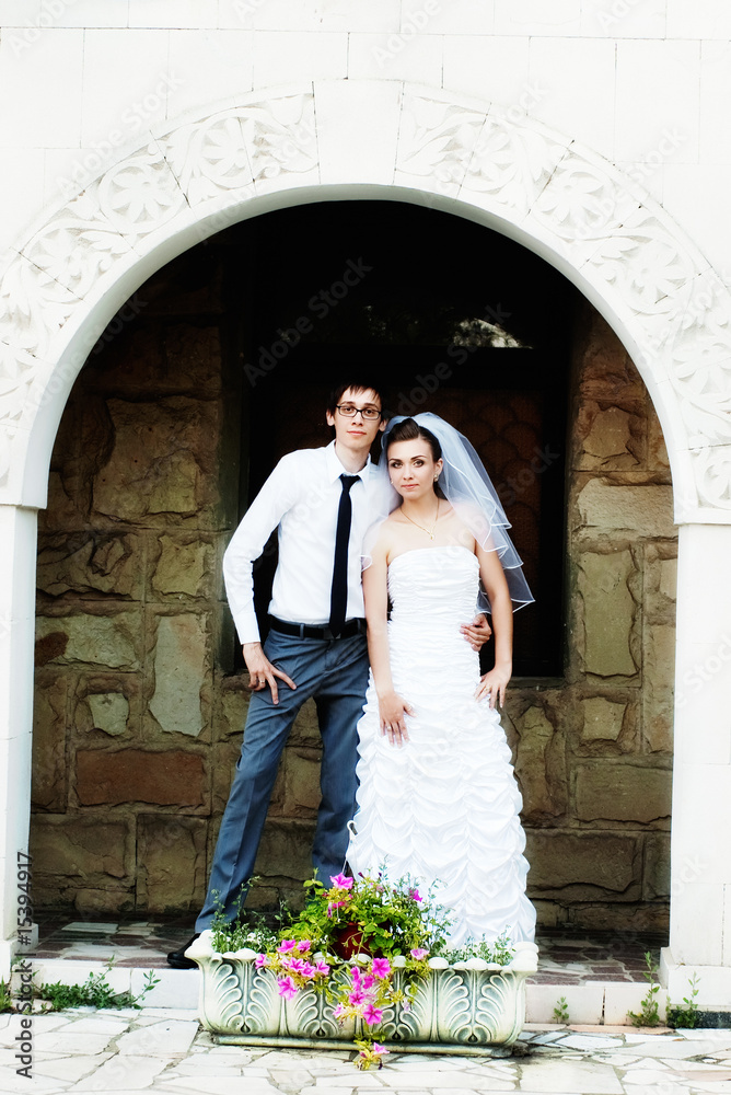 Bride and groom standing under white arch with flowers Bride and groom standing under white arch with flowers