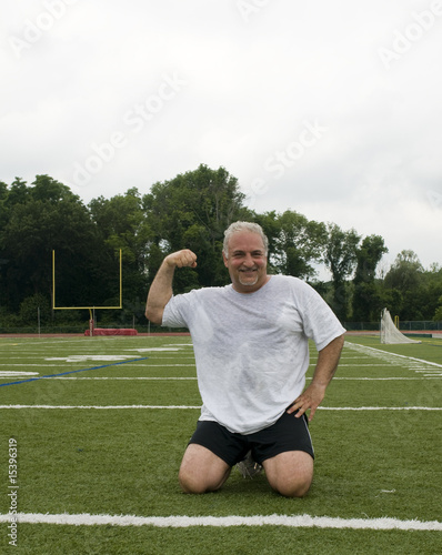 middle age man making muscle and exercising on sports field