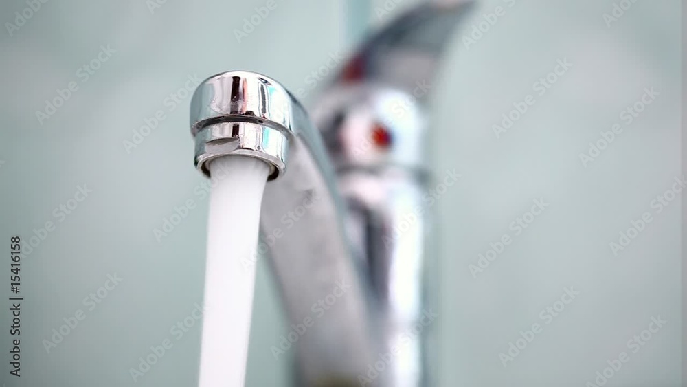 Man's hand starting and stopping tap water in bathroom