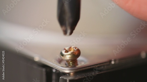 Macro of a human hand putting in and screwing in a small bolt