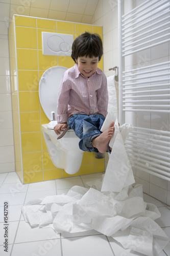 Little boy is making a mess with toiletpaper photo