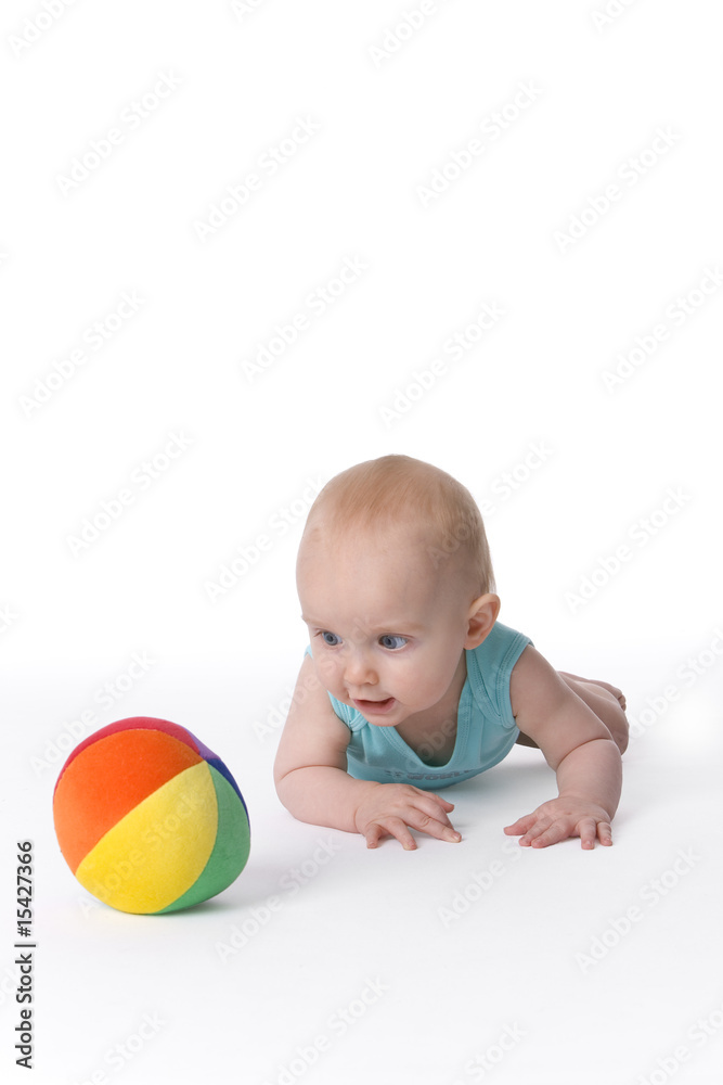 Baby boy crawling to a soft colored toy ball Baby boy crawling to a soft colored toy ball