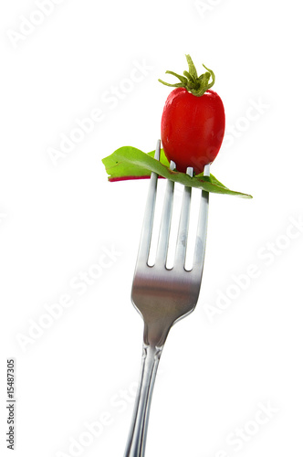 cherry tomato and spinach leaf on a fork, over white