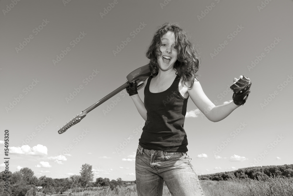 Teenage girl with  electric guitar in field monochrome