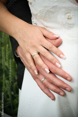 Wedding hands with rings on pregnant bride