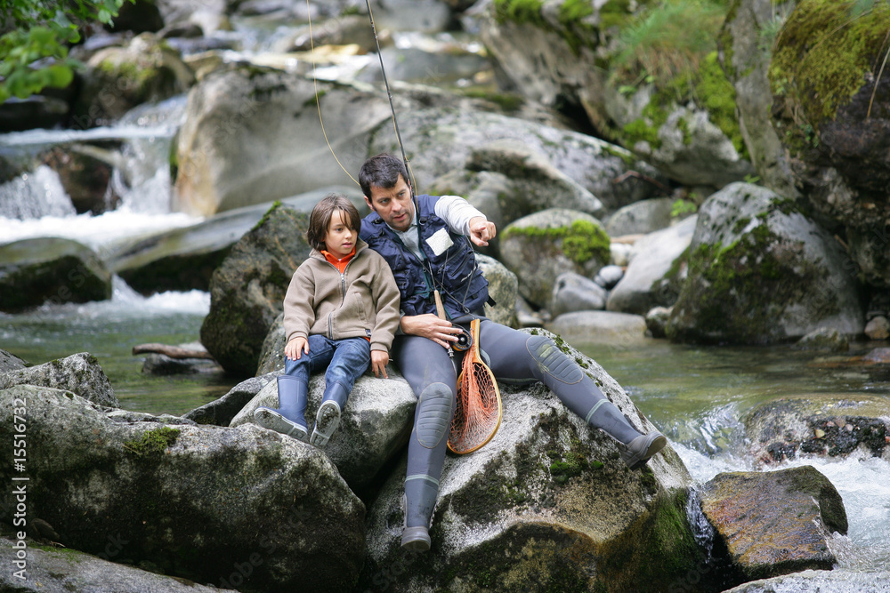 Homme et petit garçon regardant au loin au bord d'une rivière Homme et petit garçon regardant au loin au bord d'une rivière