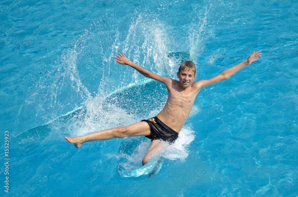 Sportlicher Junge springt fröhlich in den Pool