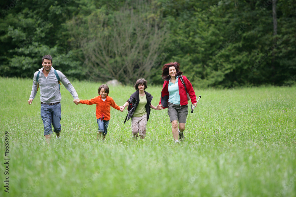 Couple avec enfants courant dans l'herbe à la campagne Couple avec enfants courant dans l'herbe à la campagne