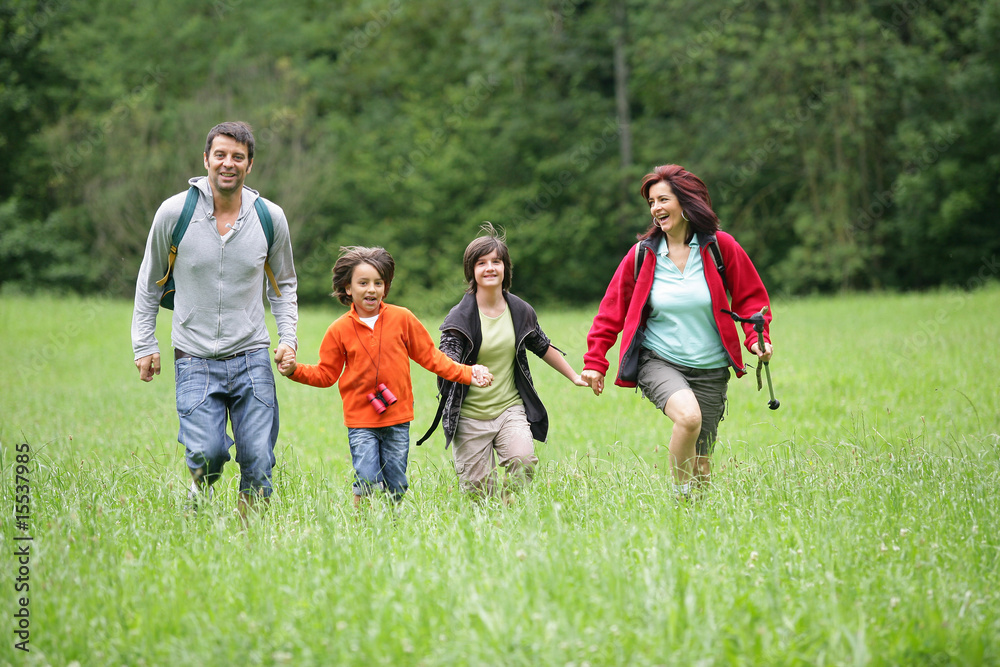 Parents avec enfants courant dans l'herbe à la campagne Parents avec enfants courant dans l'herbe à la campagne