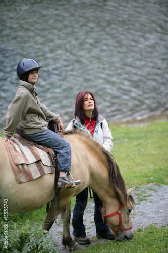 Femme près d'une adolescente assise sur un poney