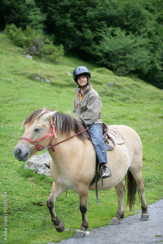 Jeune fille souriante assise sur un poney