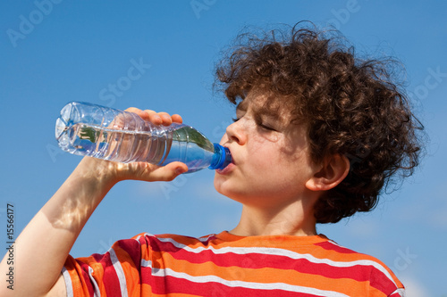 Boy drinking water against blue sky