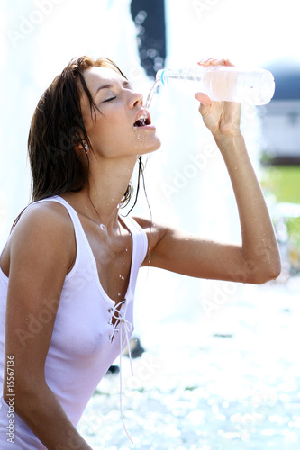 young woman drinks water from a bottle