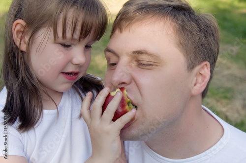 A girl feeding her daddy with apples having fun