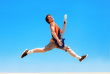 Young man with guitar jumping on a background of blue sky