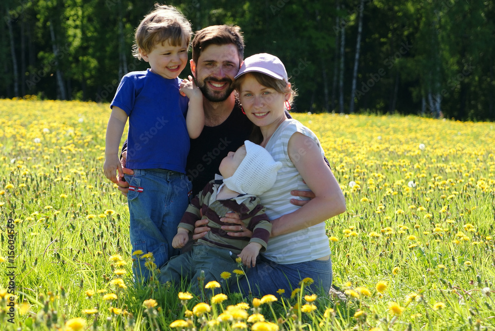 Happy family of mother, father and two sons in dandelion field