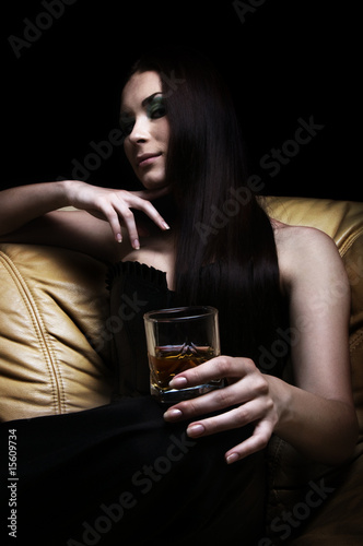 Young woman lying on sofa with a glass of whisky
