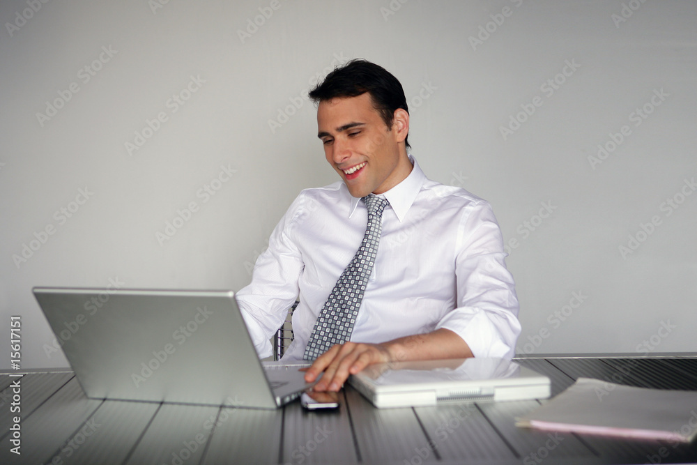 homme d'affaires souriant assis devant un ordinateur portable homme d'affaires souriant assis devant un ordinateur portable