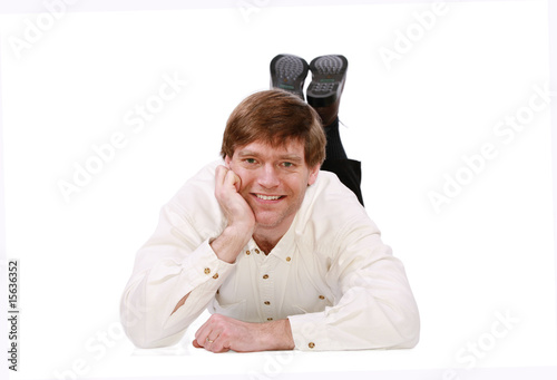 Handsome business man lying on floor relaxing, chin on hand photo