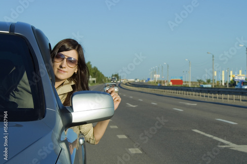 Happy young woman driving silver car