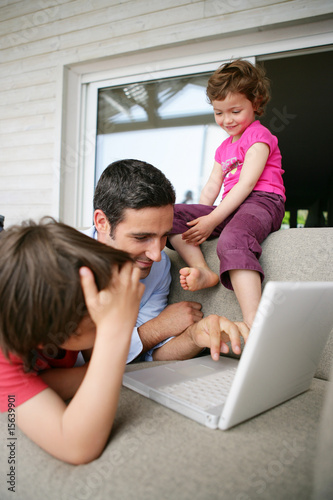 homme avec enfants étendu sur un canapé devant un ordinateur