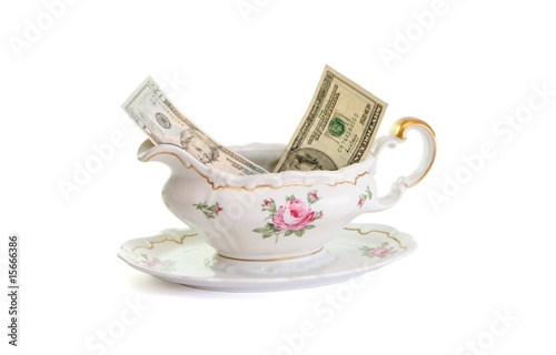 Vintage porcelain sauce-boat with dollar bills isolated