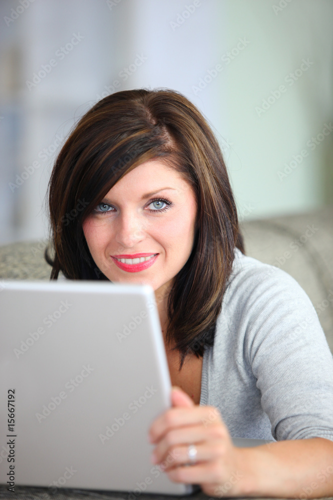 femme souriante étendue sur un canapé devant un ordinateur femme souriante étendue sur un canapé devant un ordinateur