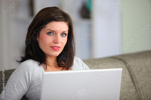 Femme assise sur un canapé devant un ordinateur portable