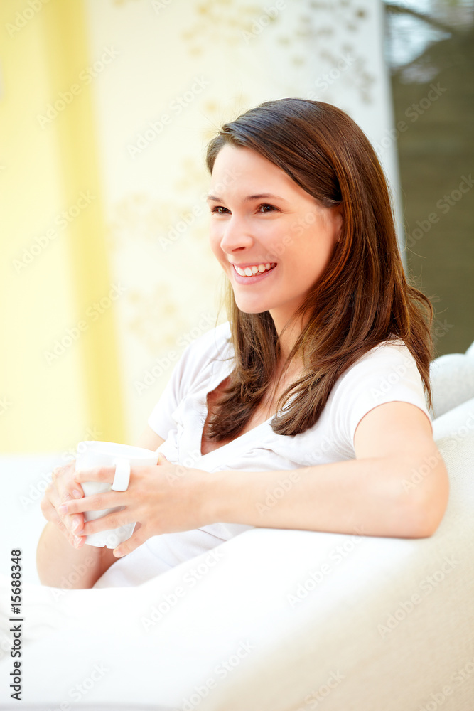 Junge Frau Zuhause mit Kaffeetasse lachend Junge Frau Zuhause mit Kaffeetasse lachend