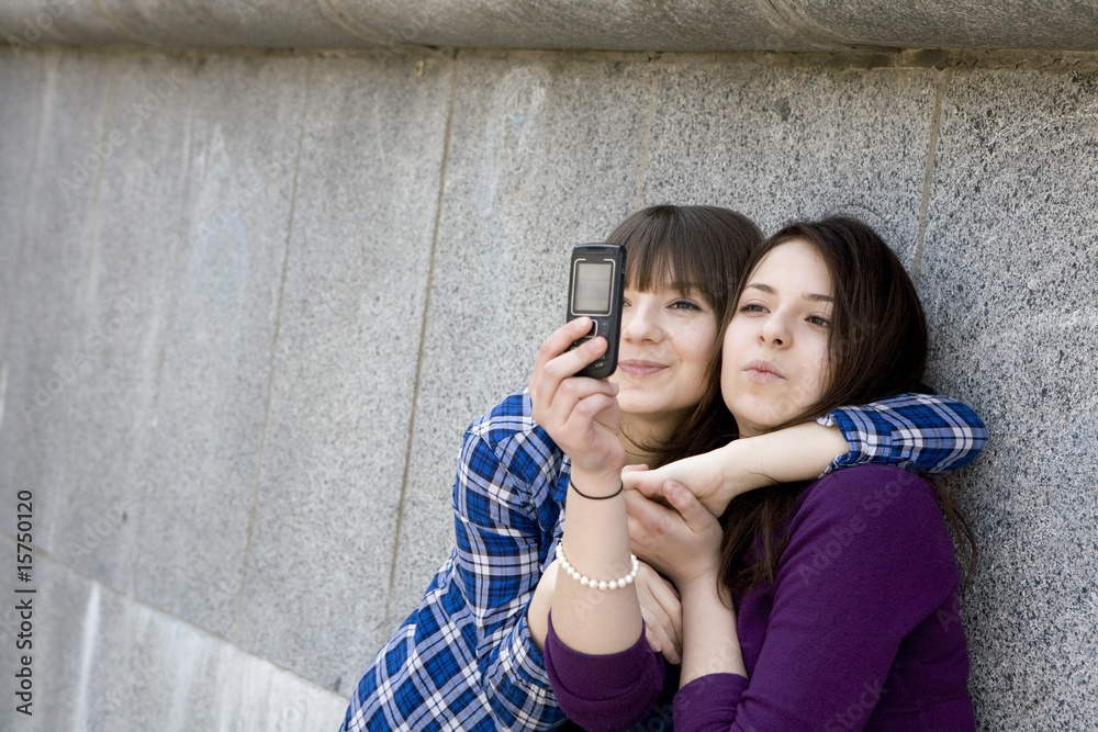 two urban teen girls taking photo by mobile phone