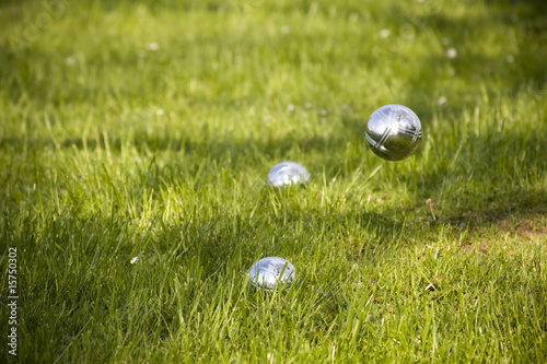 Close up of four metal petanque bowls on grass.