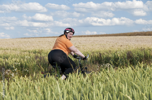 XXL-Model, Frau auf Fahrrad im Feld lacht in Kamera