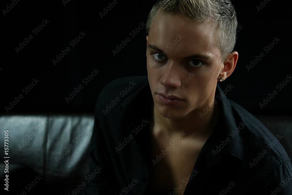 Fototapeta premium Young man on before black background on a couch