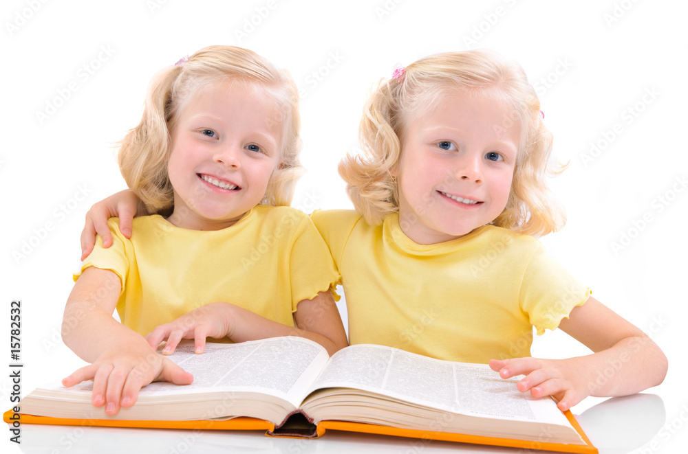 smiling little twinsgirls with book smiling little twinsgirls with book