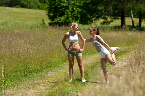 Two young women exercising in a meadow