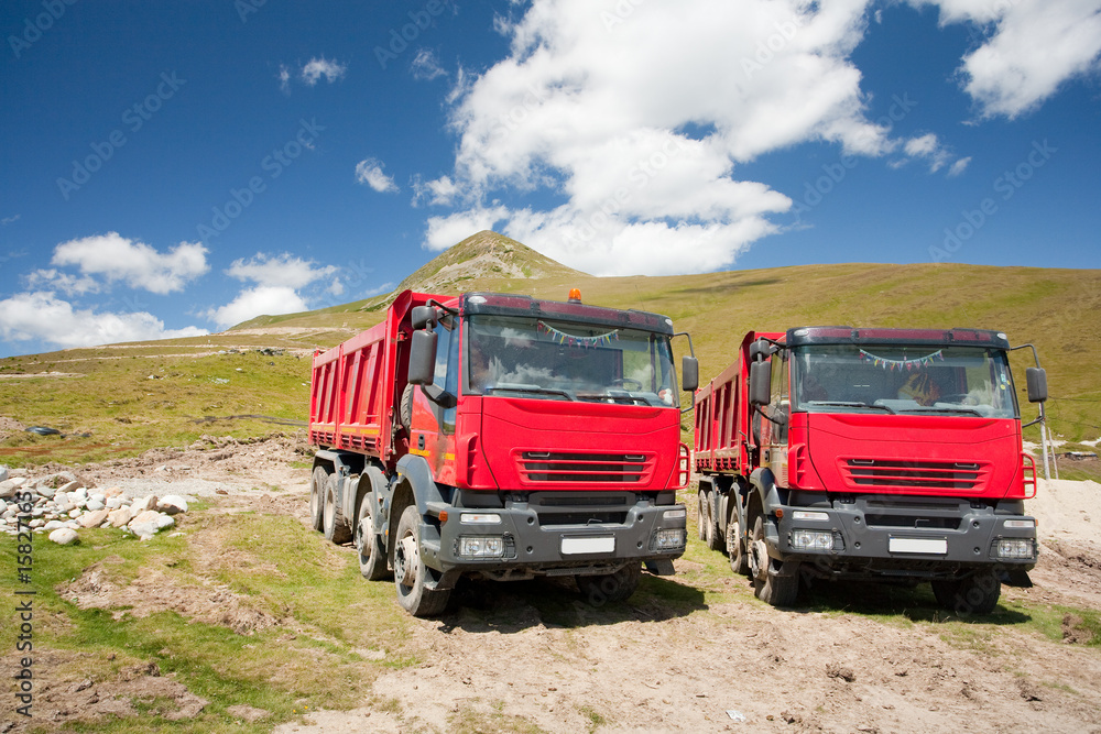 Two large red dump trucks