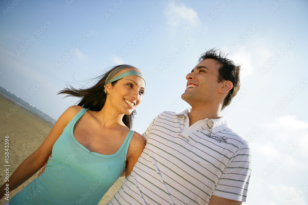 Jeune couple souriant en se baladant au bord de l'eau