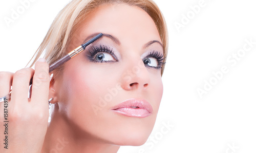 Nice caucasian model applying makeup with brush