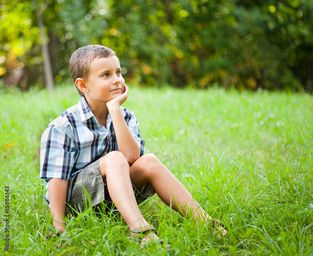 Fototapeta premium Cute kid sitting in grass