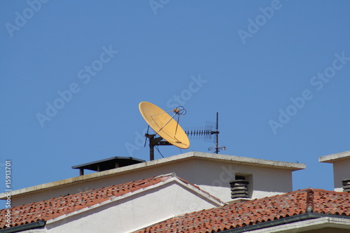 Antena parabolica amarilla en el tejado. photo