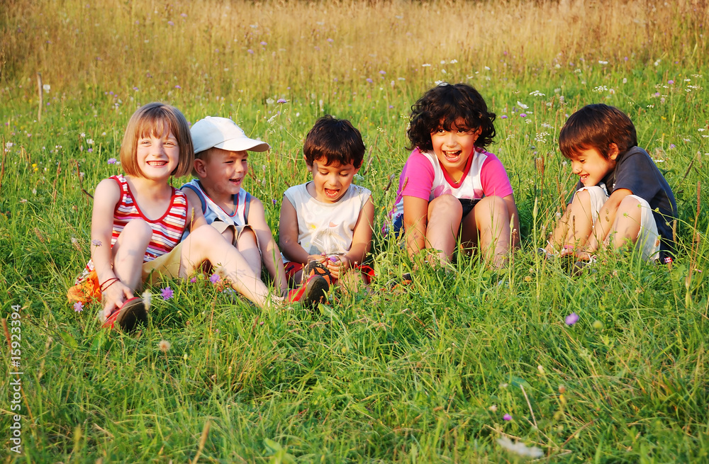 Happy little children in grass on meadow