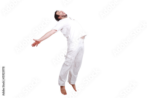 Happy young male in white clothes is jumping isolated