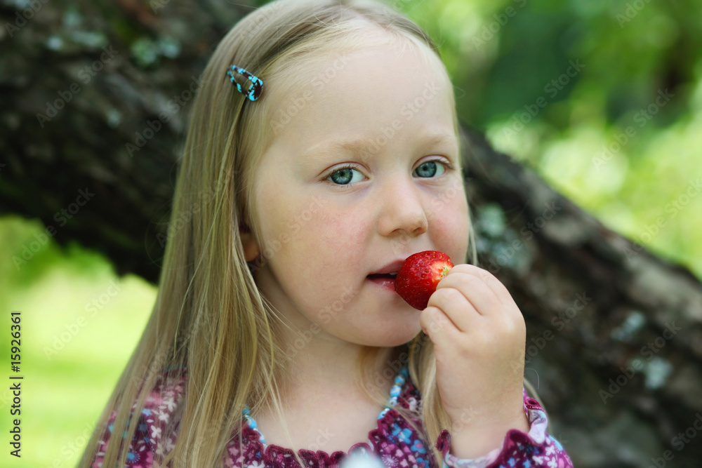 Happy little girl eating a strawberry. Happy little girl eating a strawberry.