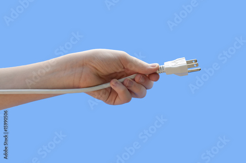 Youth hand holding electric plug isolated on teal background