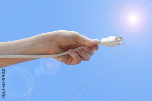 Принти на полотні Youth hand holding electric plug isolated on teal background