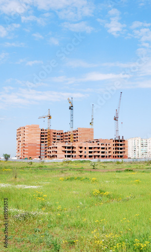residential building under construction and four cranes against