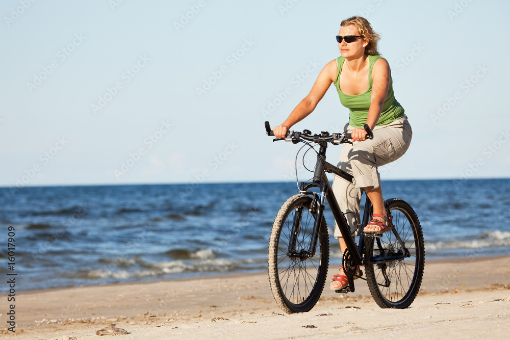 Fototapeta premium Woman riding bicycle in beach
