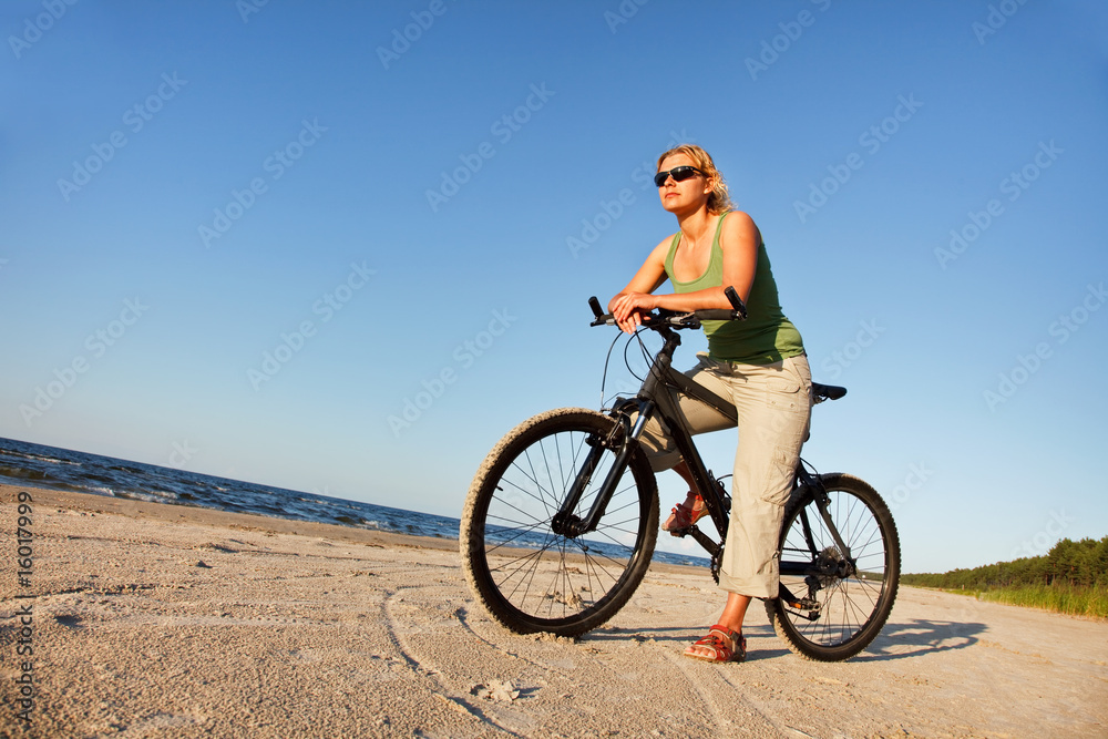 Fototapeta premium Young woman with bicycle in beach