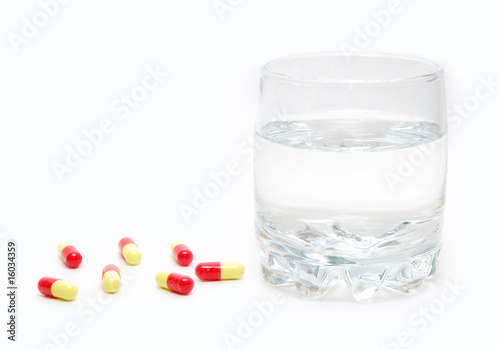 Pills and a glass of water isolated on white background